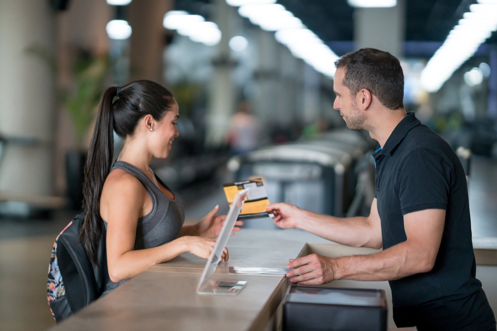 Woman at the gym talking to receptionist about membership plans